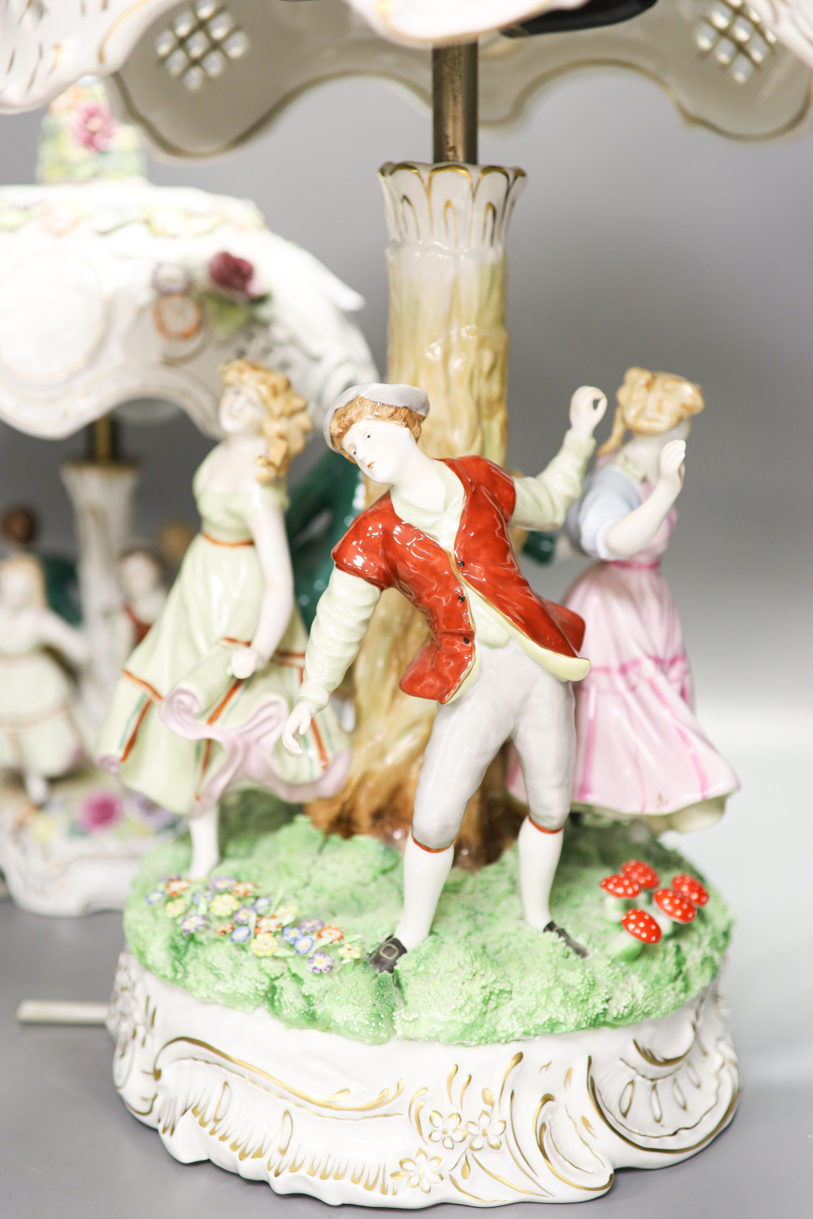 Two pairs of German porcelain table lamps, the stems modelled with figures dancing 56cm